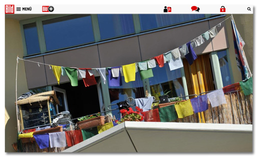 Screenshot Bild.de - Foto, das viele bunte Stoffstücke auf zwei Leinen auf einem Balkon zeigt
